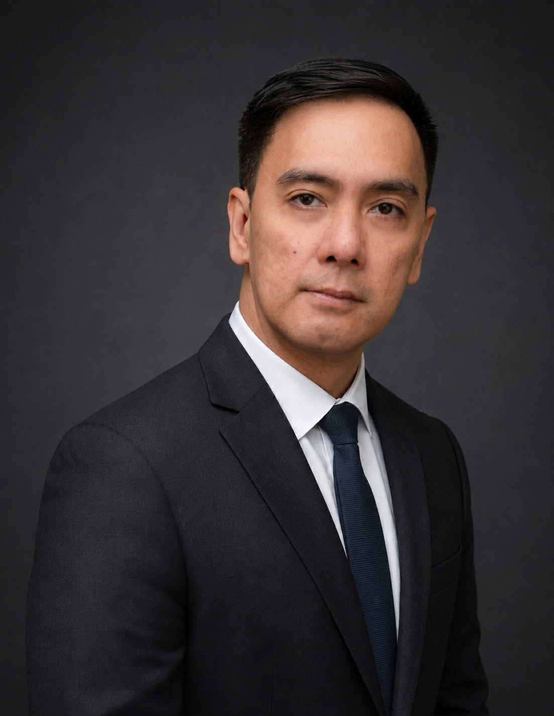 Louie Castro, Co-Founder and Chief Strategy Officer of Crevello, in a dark suit against a charcoal backdrop