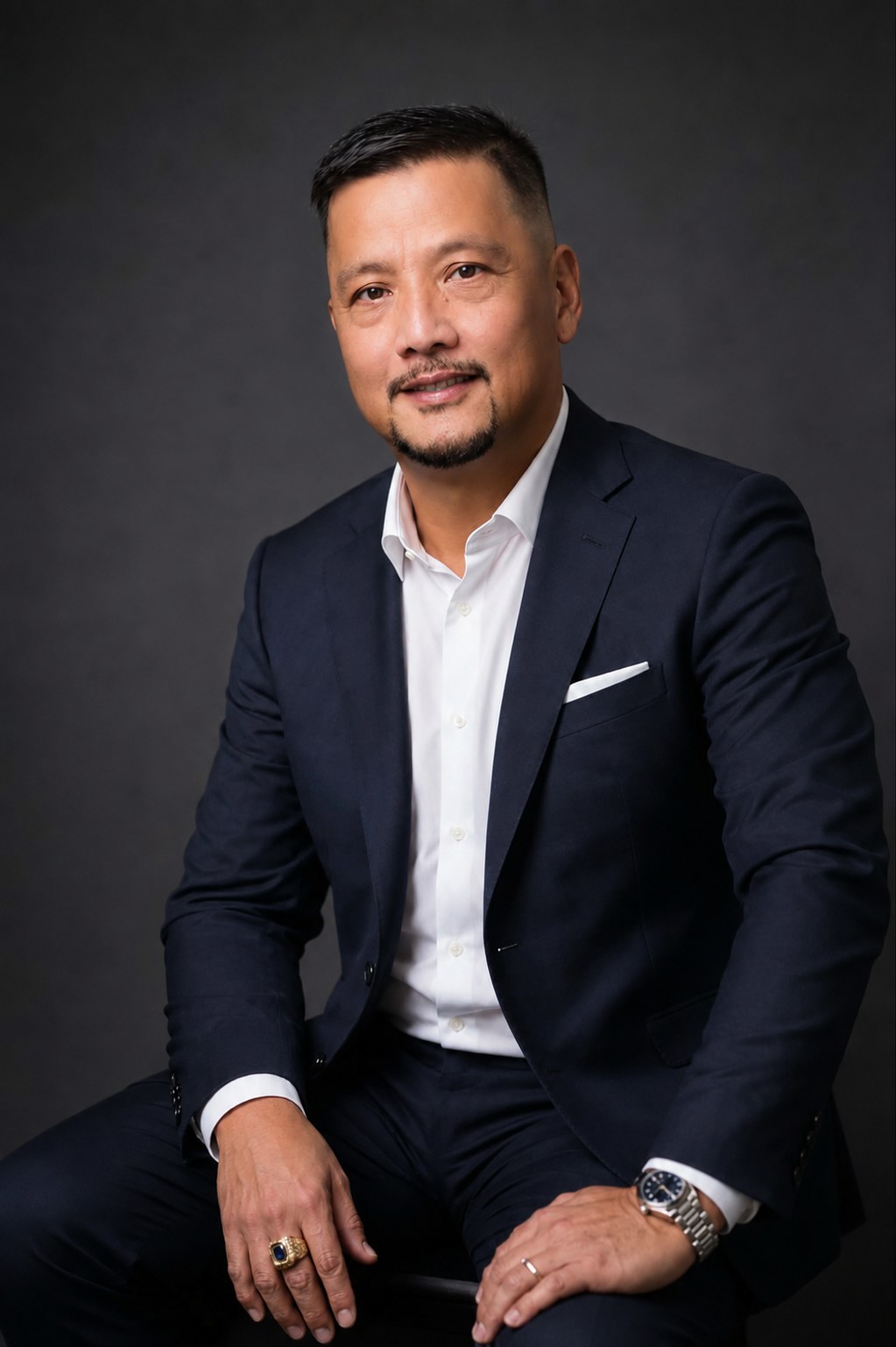 Eric Dominguez, Co-Founder and Chief Operating Officer of Crevello, seated in a navy suit and open-collar white shirt against a charcoal backdrop